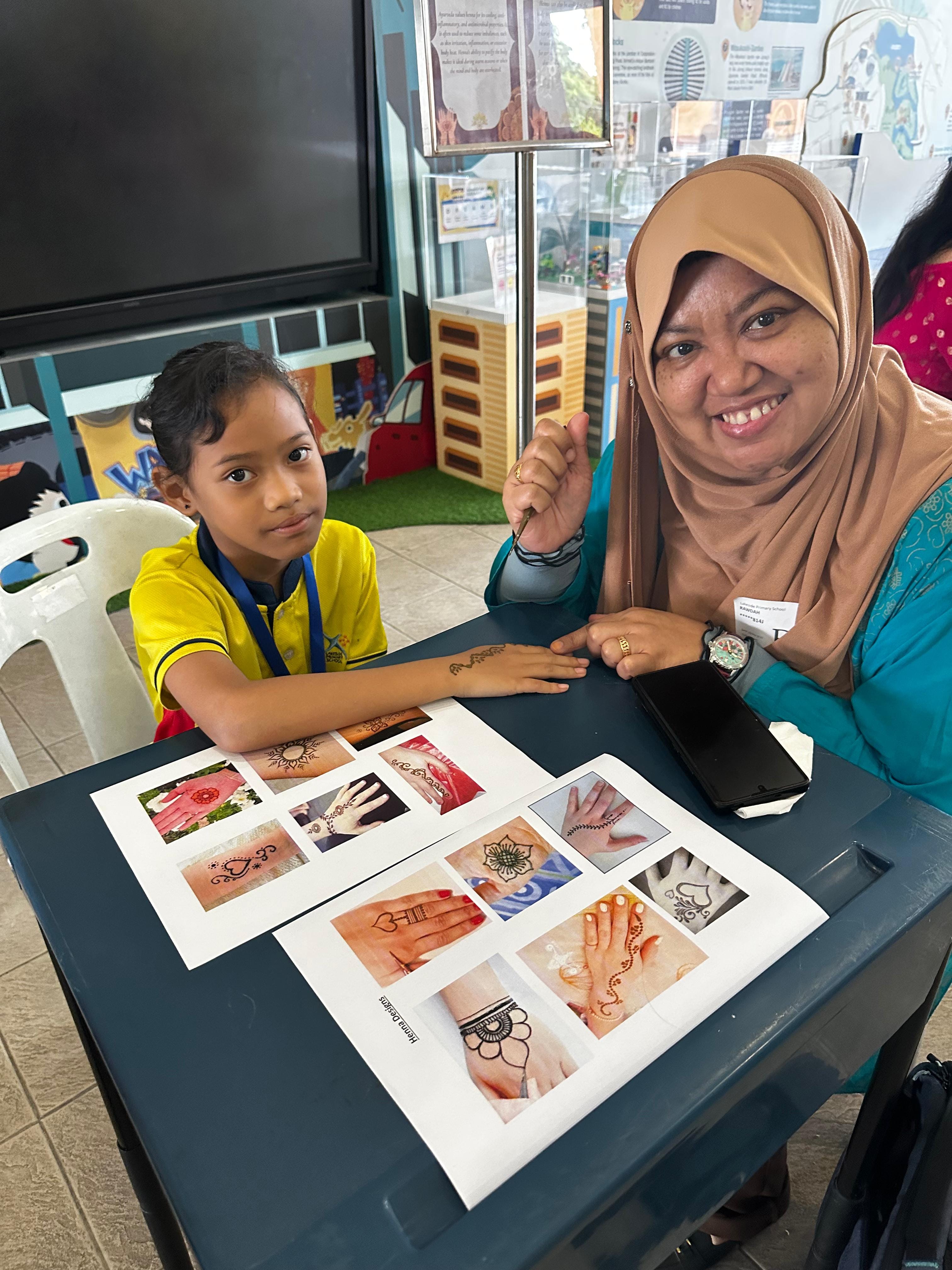 A student having festive henna art done on her hand